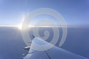 Sky scape view from clear glass window seat to the aircraft wing of the plane, traveling on the clouds and sunshine with blue sky