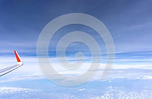 Sky scape view from clear glass window seat to the aircraft wing of the plane, traveling on the clouds and vivid blue sky