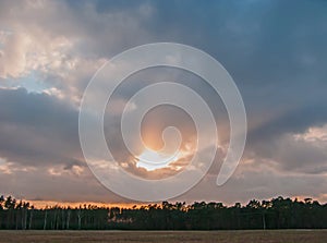 Sky with sun setting behind the clouds.