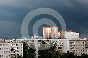 The sky is very dark blue over multi storey buildings before a thunderstorm