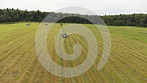 Sky view of big grey tractor moving with working attached red round shaped rakes