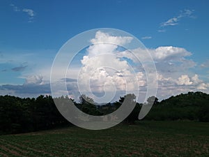 Sky with white rainy clouds in the green farmland. close up view of cloud,