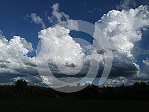 Sky with white rainy clouds in the green farmland. close up view of cloud,