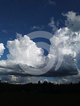 Sky with white rainy clouds in the green farmland. close up view of cloud,