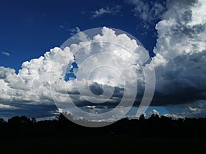 Sky with white rainy clouds in the green farmland. close up view of cloud,