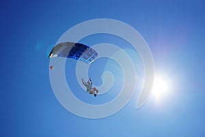 Skydiver with a blue parachute close up under sunshine