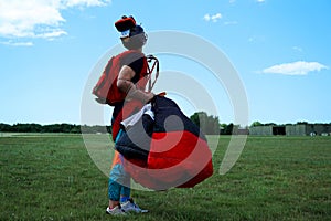 Skydiver in a field on green grass looks into the blue sky