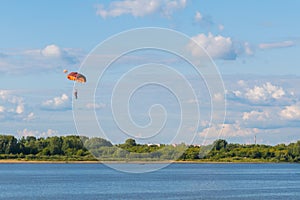 Skydiver flying with parachute against blue sky - extreme sport concept