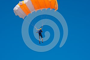 Skydiver is flying with parachute in blue sky