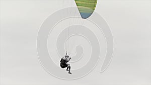 Skydiver is going to land and finish his flight. Action. Bottom view of a landing parachutist with a cloudy heavy sky on