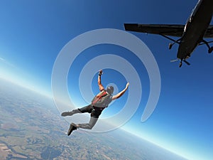 Skydiver jumps from a black plane on a hot day with clear skies.