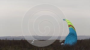 Skydiver is landing on the grass field. Action. Autumn landscape with a landing parachutist with a mountains and cloudy