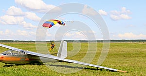 Skydiver landing near glider.