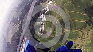 Skydiver parachuting above green fields. River. Extreme activity. Adrenaline.