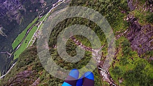 Skydiver parachuting above mountains covered by green woods. Extreme sport.