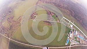 Skydiver parachuting in cloudy sky above green field. Extreme sport. Height.