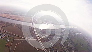 Skydiver parachuting in cloudy sky above green field, river. Height. Scenery.