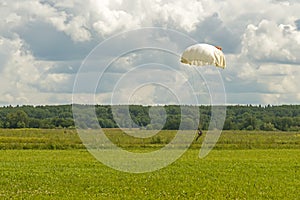 Parachutist before touchdown in a field of grass