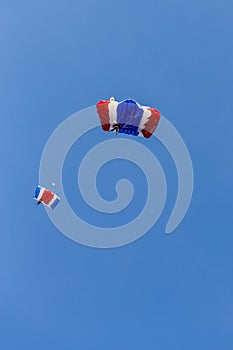 Skydiver team in colorful parachute gliding after free fall jump