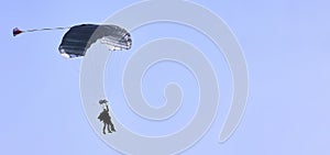 A skydiver with a white parachute canopy against a blue sky and white clouds, close-up.