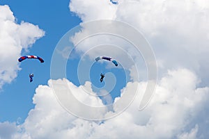 Skydivers among the clouds and blue sky photo