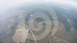 Skydivers fly in sky over green field. Colorful parachutes. Extreme sport.