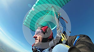 Skydivers flying in tandem under the open parachute. Slow Motion