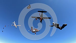 Skydivers jump out of tow airplanes with blue skies.