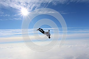 Skydiving. Skydiver is flying above white clouds.