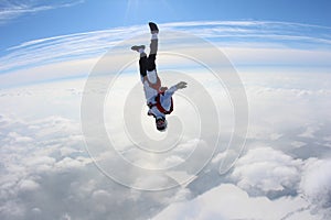 Skydiving. Skydiver in head down position is falling above clouds.
