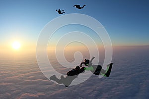 Skydiving. Sunset jump. Skydivers are above pink clouds.