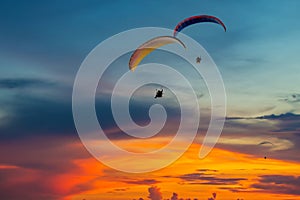 Skydiving sunset landscape of parachutist flying in soft focus. Para-motor flying silhouette with sun set. Silhouette of paraglide