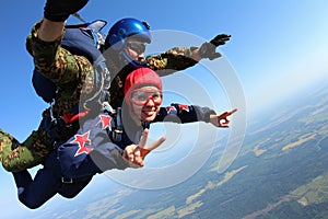 Skydiving tandem is falling in the blue sky.