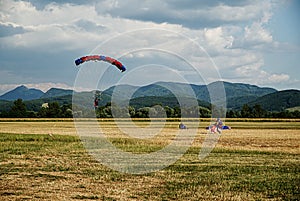 Skydiving, tandem parachutists in the sky and two parachutist on the ground