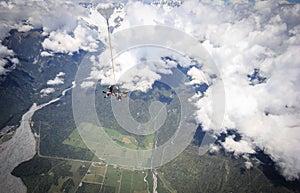 Skydiving in tandem, seconds after jumping out of plane, tilted shot with clouds in backdrop