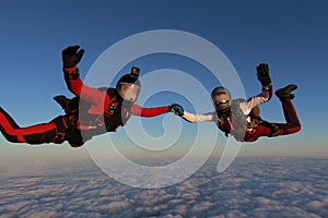 Skydiving. Two skydivers are flying in the sunset sky.