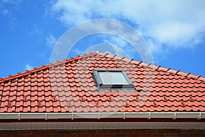 Skylight on red ceramic tiles house roof with rain gutter. Skylights, Roof Windows and Sun Tunnels. Attic skylight solution photo