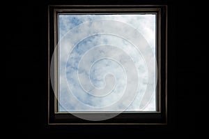 Skylight surrounded by darkness. Blue sky and clouds. Conceptual metaphor.