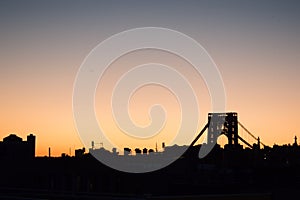 Skyline of Fort Lee with George Washington Bridge silhouetted against a sunset sky