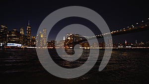 Skyline of New York with lit modern skyscrapers and the famous Brooklyn Bridge at night