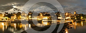 Skyline at night of Murten in Switzerland with the harbor and pier and boat in the foreground