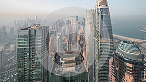 Skyline panoramic view of Dubai Marina showing canal surrounded by skyscrapers along shoreline night to day timelapse