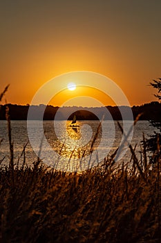 Sail boat shadow with Clear outline of the sun at Sunset with beautiful skyline over lake Zorinsky Omaha Nebraska