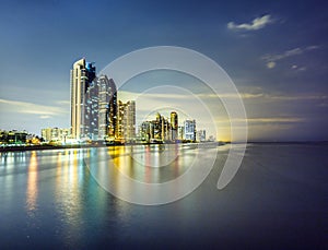 Skyline of Sunny Isles Beach by night with reflections at the surface of the ocean