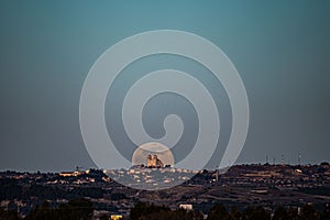 skyline of the town of Campo Real, Madrid, with the full moon of February behind the church.