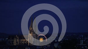 Skyline of UNESCO world heritage site town Regensburg with spinning Octoberfest ferris wheel at night