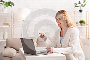 Skype lessons. Woman is teaching online, sitting at table,