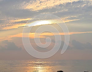 Skyscape with Bright Golden Yellow Sunbeams radiating in Cloudy Sky at time of Sunrise over Ocean - Natural Background