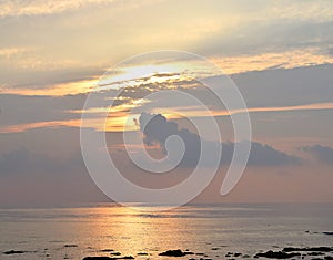 Skyscape with Bright Golden Yellow Warm Colors in Cloudy Sky at time of Sunrise over Ocean - Natural Background