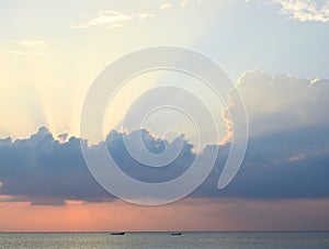 Skyscape at time of Sunset - Bright Golden Sunrays spreading through Clouds with Orange sky at Horizon over Blue Sea Water